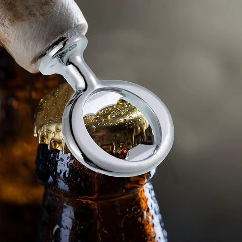 Close-up of a silver metal ring-style bottle opener prying a beer cap from a bottle