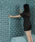 Person installing Kickass Heavy Duty Sound Proof Padding on wall, showcasing High Density Acoustic Foam Rolls in blue.