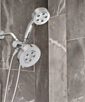 Dual Shower Head With Six Spray Modes, Polished Chrome, 2.5 GPM Water Saving Flow mounted on a tiled wall.