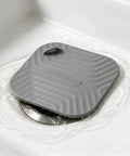 Shower Drain Cover Tub Stopper Square Silicone Floor Drain Cover resting on a shower drain, showing flexible gray silicone material.