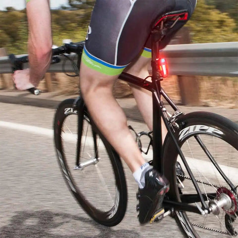 Cyclist riding on road with Lumina 1000 Boost Front Bike Light with Sabre 110 Rear Light USB Rechargeable LED Set