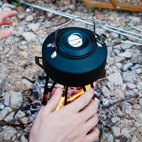 Close-up of Ultra Lightweight Portable Campfire Tripod For Outdoor Cooking over flame with hands adjusting kettle