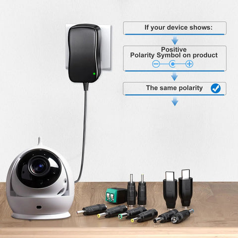 Universal 48W AC DC Power Adapter with 11 interchangeable tips and USB C output shown with a camera and tips on a table