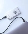 USB4 NVMe Enclosure With Active Cooling Fan And Solid Aluminum M.2 SSD Case connected to a Mac laptop.