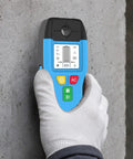 6-in-1 Stud Finder Wall Scanner Auto Shutoff LCD (Blue) held against concrete wall, showing detailed LCD screen and buttons.