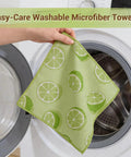 Microfiber cleaning cloth with lime/lemon print, green, held by hand beside a front-loading washer