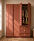 Brushed Satin Gold Wide Base Bifold Closet Door Knobs 4 Pack on terracotta cabinet with open wardrobe and dresses.