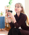 Hella Sturdy Double Wall Paper Coffee Cups With Leak Proof Lids 100 Pack 12 Oz, held by a woman, sitting indoors.