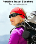 Woman hiking with portable travel speaker attached to backpack, showcasing compact design for outdoor use.