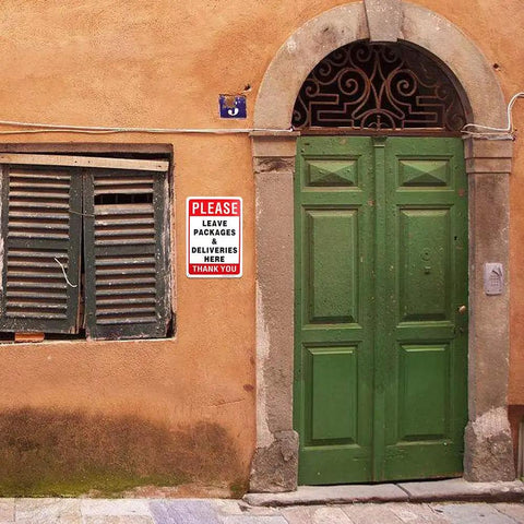 Leave Your Packages Here Heavy Duty Aluminum Front Porch Drop Off Sign 12X8 Inches on a wall near a green door for outdoor use.