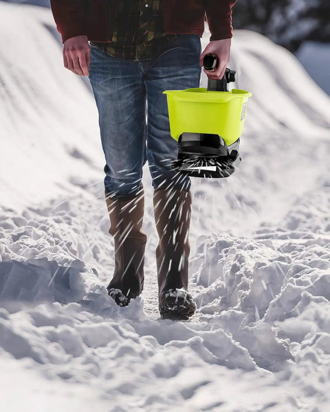 Person using All Season Handheld Seed And Fertilizer Spreader For Lawns, 18V Battery Compatible, spreading salt on snowy path