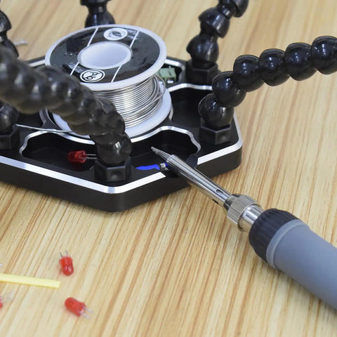 Pro Grade Helping Hands Third Hand Soldering Station with four magnetic arms and soldering iron on wood surface