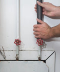Hands installing Foam Pipe Insulation Sticks For Hot And Cold Water Lines Pre Slit With Self Sealing Edge 0.75 Inch By 1 Foot Black