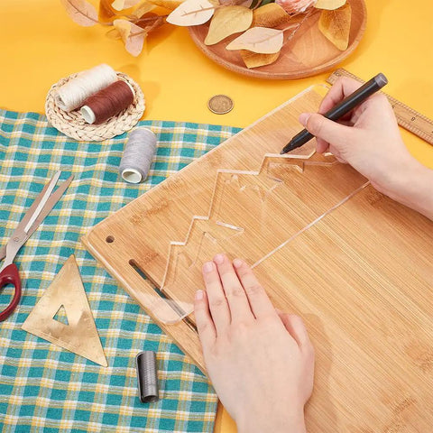 Person tracing with a pen on a wooden board using Slick Clear Acrylic Mountain Router Template For Precision Wood Inlay Projects Features Built Different Anti Scratch Layer To Level Up Your Charcuterie Board Sign Crafting Game.