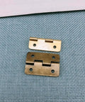 Close-up of two antique bronze mini iron hinges from Forty Two Piece Antique Bronze Mini Iron Hinges Set With Rounded Corners In A Sturdy Wooden Gift Box.