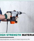 Rotary hammer drill in use drilling concrete; gray and orange body with gloved hands gripping the tool