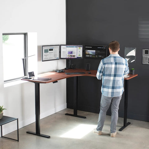 VIVO Corner Standing Desk In Dark Walnut L Shaped Electric Height Adjustable Workstation with dual monitors in use.