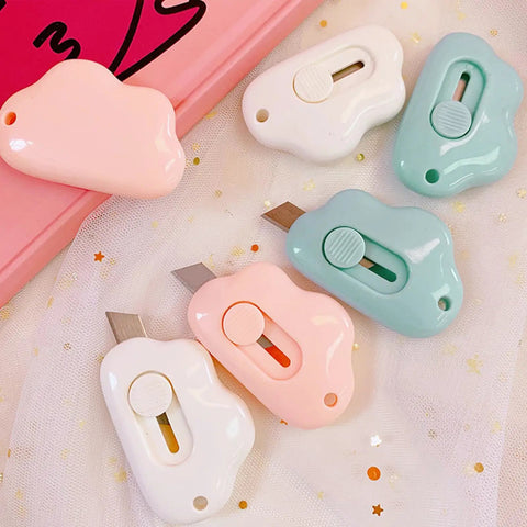 9 Pack Retractable Box Cutter Set with Cloud Charm featuring mini cutters in pink, white, and blue on star-patterned fabric.