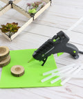 Mini Size Hot Glue Sticks For Glue Guns 0.27 Inch Diameter 4 Inch Length All Purpose All Temperature 100 Pack Clear Built For DIY Projects Arts And Crafts And Handy Repairs shown with glue gun on wooden table