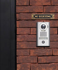 Brick wall with mounted brass No Soliciting sign six point five inch classic art deco style with brushed matte finish.