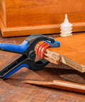Medium Bandy Clamps Set For Woodworking With Easy Squeeze One Handed Operation holding wood edge with glue bottle on table