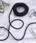 Braided black graphite packing rope, 5.5 yards, for mechanical seals and pump valves; coiled with calipers and scissors nearby.