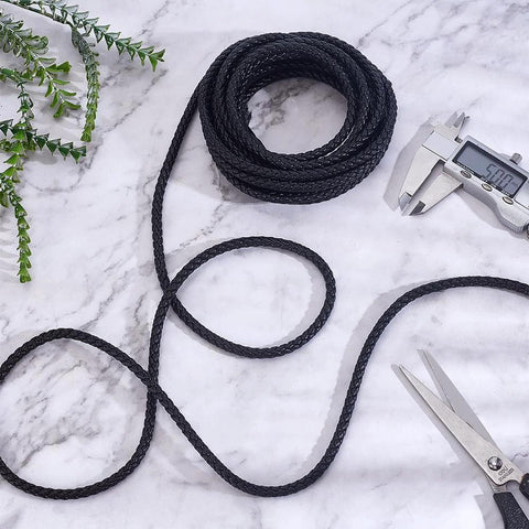 Braided black graphite packing rope, 5.5 yards, for mechanical seals and pump valves; coiled with calipers and scissors nearby.
