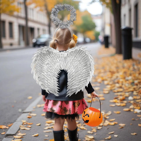 Child wearing Celestial Silver Angel Wings Headband Set With Feathered Design For Halloween Cosplay Carnival Party Accessories And Festival Looks Totally Perfect For Girls Costume Or Dress Up, walking on leaf-covered street, holding pumpkin bucket.