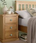 Solid Green Ceramic Cabinet Knobs In A Ten Piece Bundle, 34mm Drawer Pulls on a wooden nightstand beside a bed.