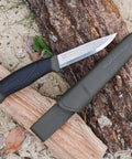 Companion Carbon Steel Fixed Blade Knife With Sheath 4.1 Inch Blade Military Green resting on log outdoors.