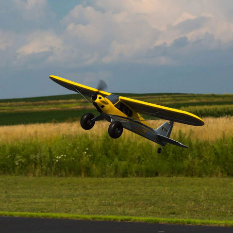 RC Airplane Carbon Cub S 2 1.3m ready to fly with SAFE technology in action outdoors, yellow and gray design, no battery and charger