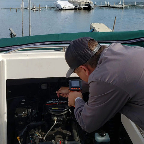 Person using Camera Assisted Retrieval Tool With 32 Inch Bendable Gooseneck Four Prong Claw Live 480P Video On Two Point Eight Inch LCD Four LED Lights Magnetic Tip Pulls Ferrous Objects From Tight Spaces For Contractors Mechanics And DIY Pros Orange on boat engine.