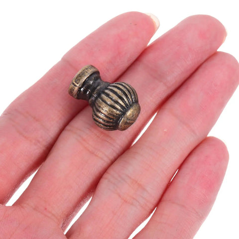 Close-up of Vintage Pumpkin Drawer Pulls 12 Piece Set Old School Round Cabinet Knobs For Jewelry Boxes Cupboards And Furniture Hardware In Small Lantern Green Bronze Finish With A Comfy Grip on a hand.