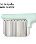 OXO Tot crinkle cutter for kids with mint-green handle and stainless steel ribbed blade, close-up view.