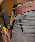 Black folding pocket knife with belt clip, side view clipped to jeans pocket.