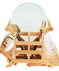 Heavy Duty Bamboo Dish Drying Rack Three Tier Collapsible Wooden Drainer With Utensil Holder, holding plates, glasses, and forks.
