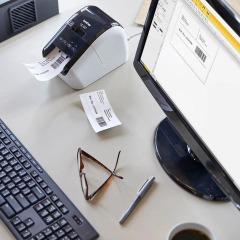 Turbo Fast Label Printer For Shipping And Address Labels With Auto Cutter, Crisp 300 DPI Black And Red Output, Works With DK-2251 Label Rolls For Packages And Envelopes, Renewed on a desk next to computer monitor and keyboard