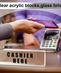 Cashier here sign displayed on a clear acrylic block next to a payment terminal