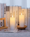 White Flameless Candles Set Of 2 2.2x5 Inch LED Pillar Candles With Remote, Timer, Battery Operated, on a shelf with books