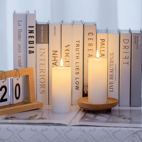White Flameless Candles Set Of 2 2.2x5 Inch LED Pillar Candles With Remote, Timer, Battery Operated, on a shelf with books