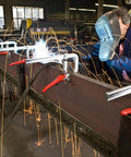 Heavy Duty 20 Inch Lever Clamp With Quick Grab Ratchet Jaw Dead Nuts Cold Drawn Steel Frame in use while welding sparks fly.