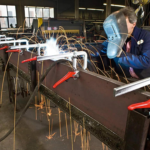 Heavy Duty 20 Inch Lever Clamp With Quick Grab Ratchet Jaw Dead Nuts Cold Drawn Steel Frame in use while welding sparks fly.