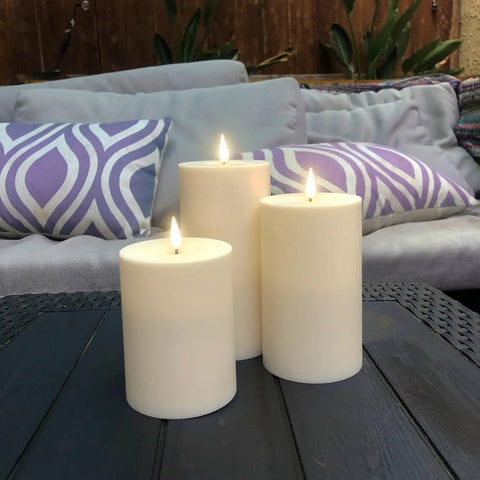 Waterproof Outdoor Flameless Pillar Candles 3 Pack In Ivory Resin on patio table, LED flicker, battery operated, 3x4, 3x5, 3x6 in