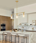 3-Light Kitchen Island Pendant Lighting in Gold Finish hanging over marble kitchen island with clear glass shades, modern dining room look