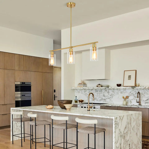 3-Light Kitchen Island Pendant Lighting in Gold Finish hanging over marble kitchen island with clear glass shades, modern dining room look