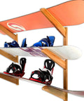 Premium Heavy Duty Solid American Oak Snowboard Wall Rack Holds Three Boards Securely with Extra Stash Zone for Helmets Goggles and Ski Poles for Your Garage or Man Cave Flex Display, showcasing snowboards and bindings.