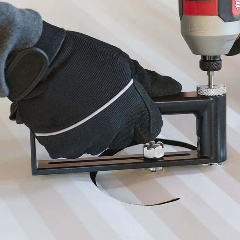 Front view of adjustable sheet metal hole cutter with drill in use, black frame and circular cut.