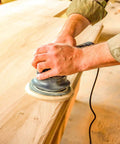Person using DA sander with Premium 5 Inch Green Film Sanding Discs 600 Grit With Hook And Loop Backing Pack Of 50 For DA Sanders Finishing Sandpaper Automotive And Woodworking Fine Cut Abrasive on wood surface.