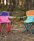 Two Kids Glow In The Dark Camping Chairs With Cup Holder And Carry Bag, colorful designs, set on a forest ground for outdoor use.