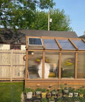 Greenhouse with solar panel installed, featuring the 50 Watt Solar Exhaust Fan For Attics, Garages, Greenhouses, Barns And Sheds With Waterproof Build, No Fuss Install, On Off Switch, Prewired For Easy Install, Solar Powered Cooling For RVs And Gable Vents, Made In USA.